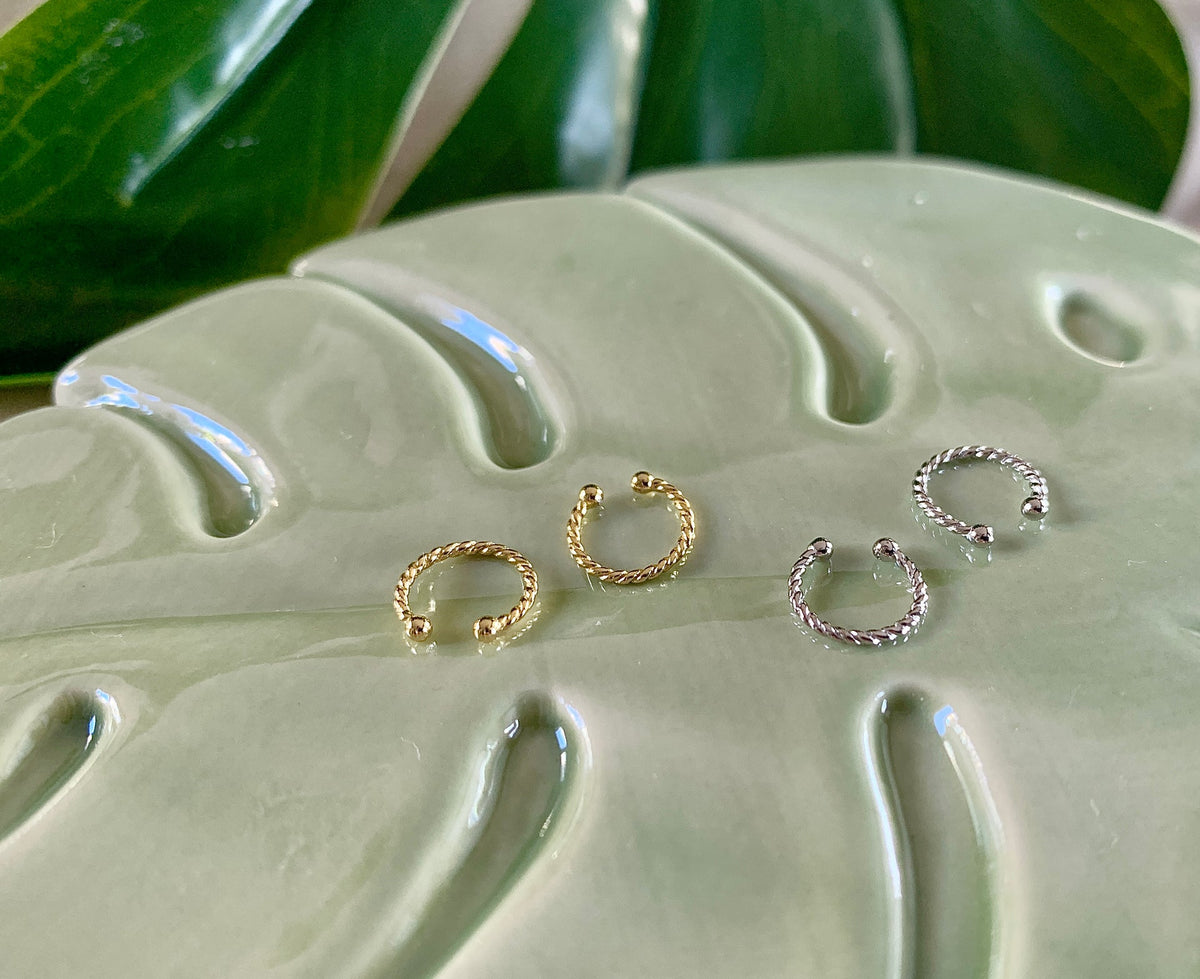 Mini Ear Cuffs in Gold und Silber gemeinsam auf einer Keramikablage